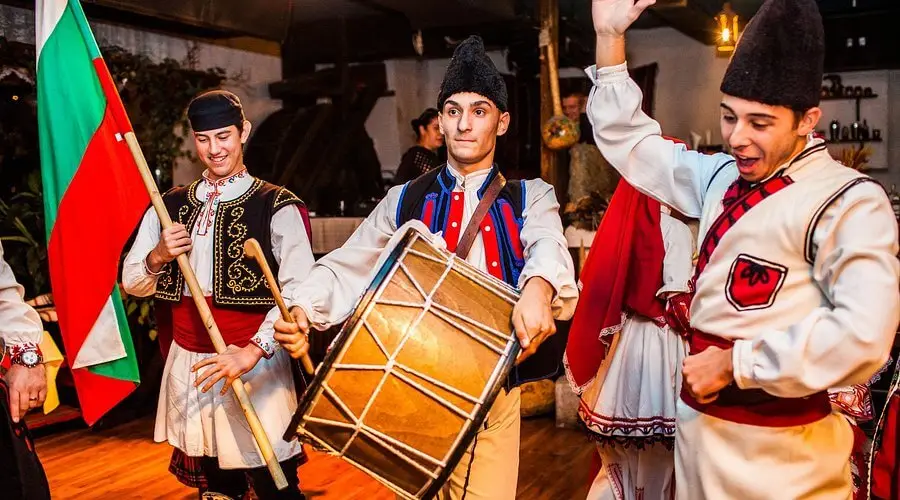 Folk musicians with a drum and the Bulgarian flag at Hadjidraganovite Kashti