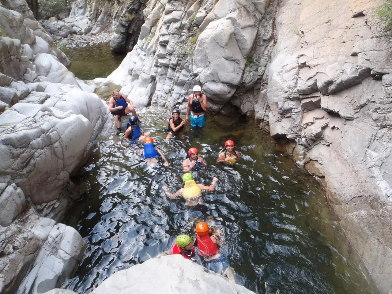 Group in helmets and life jackets standing in a canyon pool