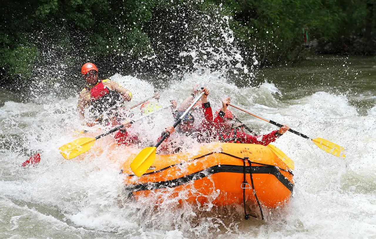 Orange raft hitting a wall of spray on the river