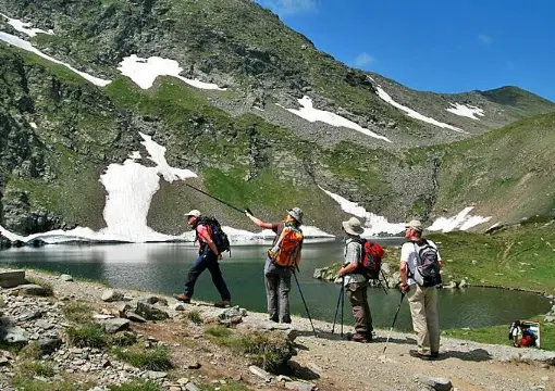 Hikers with trekking poles at the shore of a Rila lake