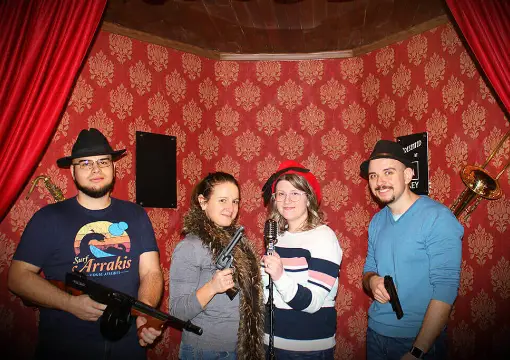 Team in gangster hats and props inside the Al Capone escape room