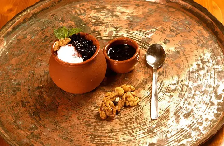 Yoghurt with jam and walnuts in clay pots
