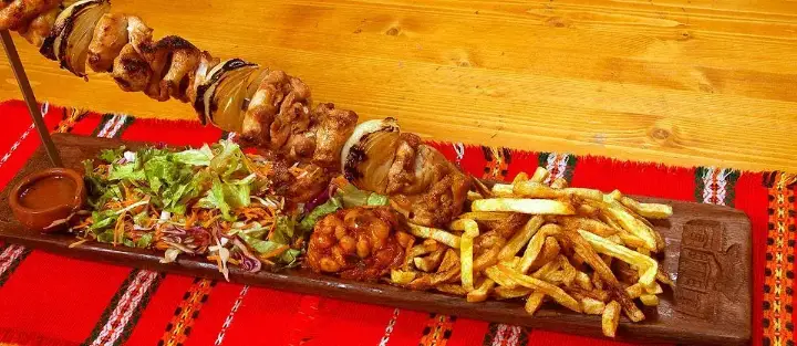 A skewer of grilled meat with chips and salad