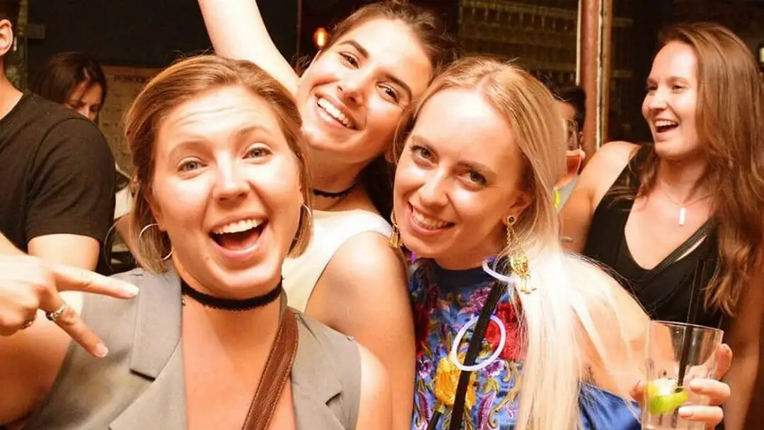 Friends laughing with drinks on a pub crawl night in Sofia