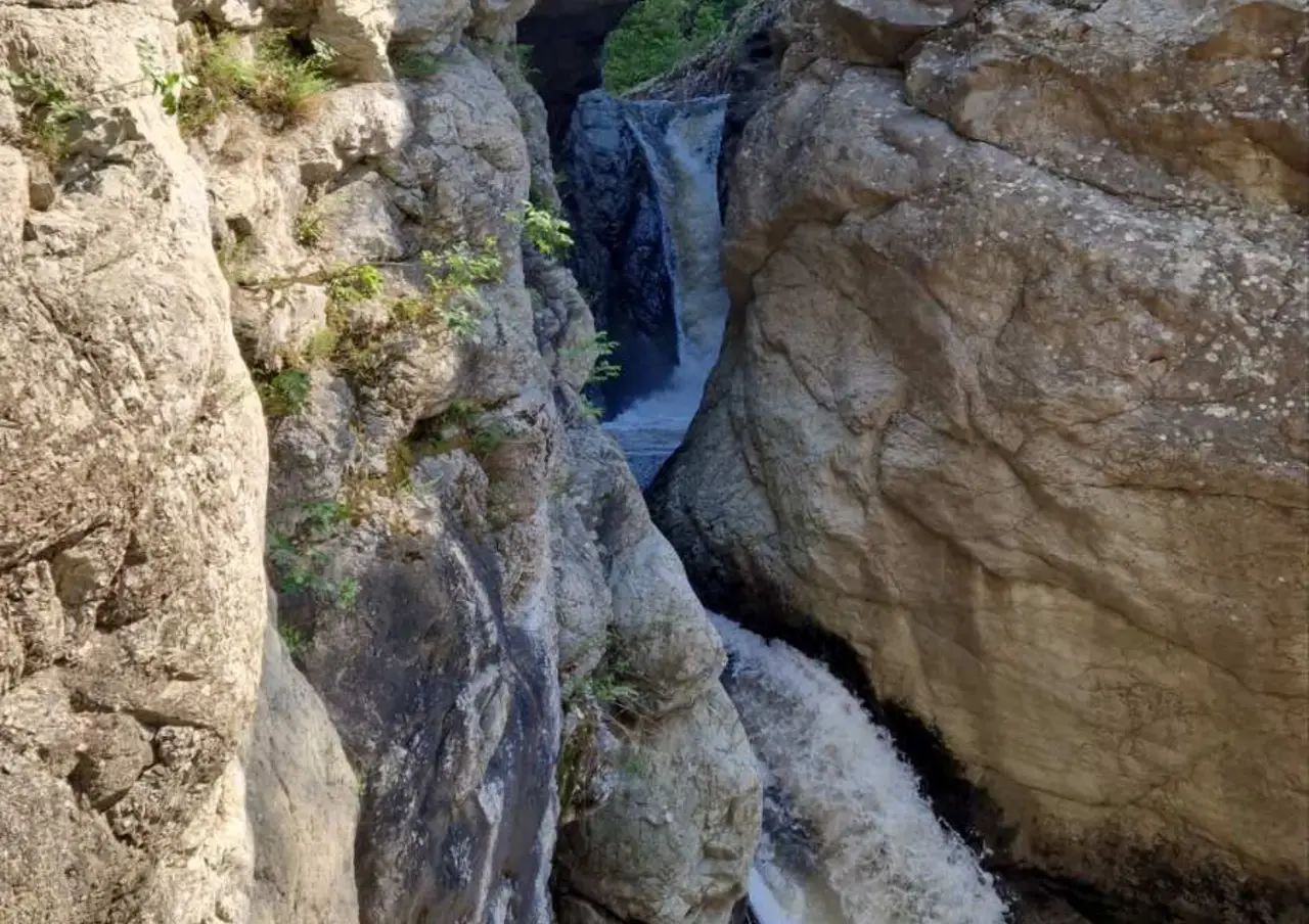 Waterfall pouring into a pool between rock walls at Kazanite