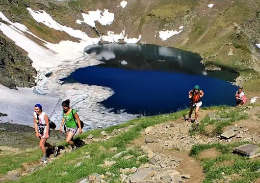 Hikers on the trail above a glacial lake in the Rila Mountains