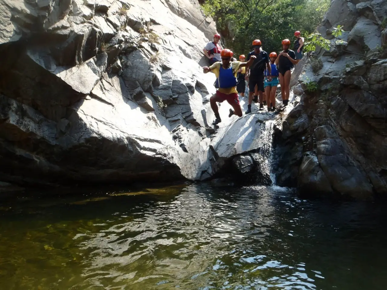 Group on a rock ledge above a dark green pool