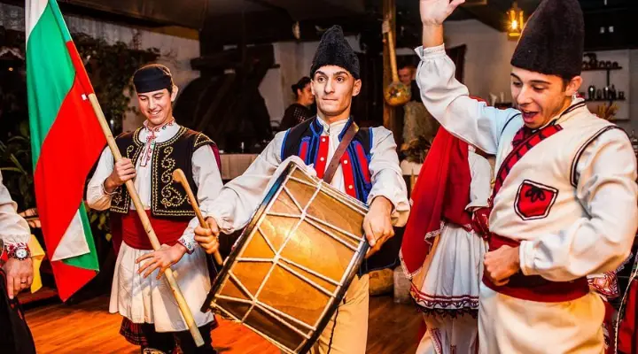 Folk musicians in costume with a drum and the Bulgarian flag
