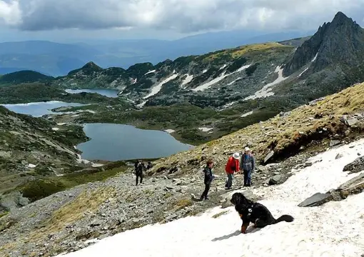 Hikers crossing a snow patch above the Seven Rila Lakes