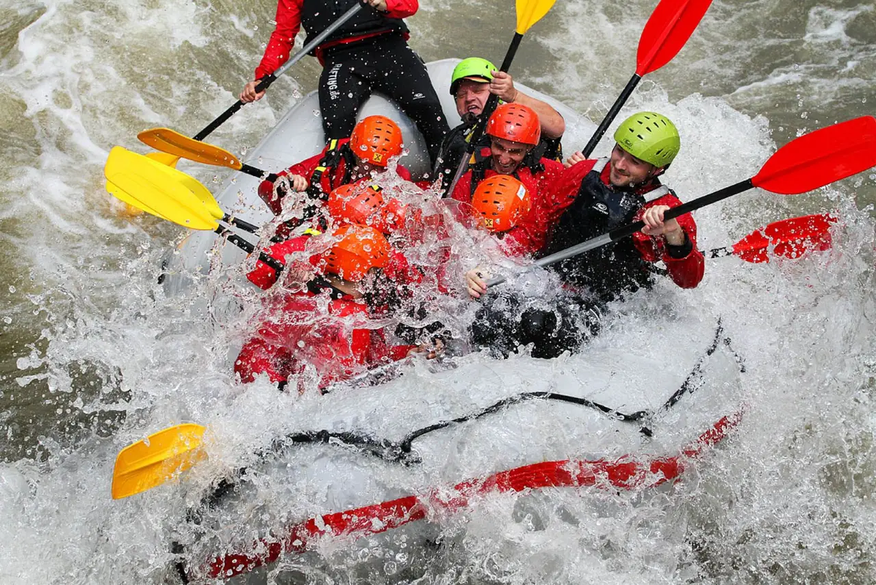 Rafting crew paddling hard through a white water wave on the Struma