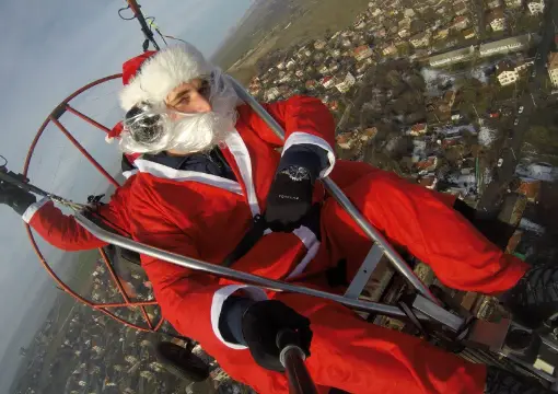 Pilot dressed as Santa flying the paramotor over a town near Sofia