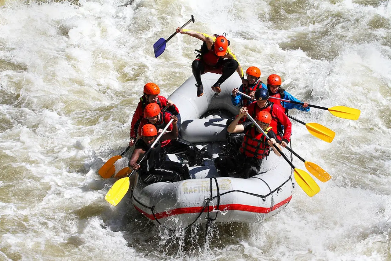 Raft with eight paddlers in red helmets riding the rapids