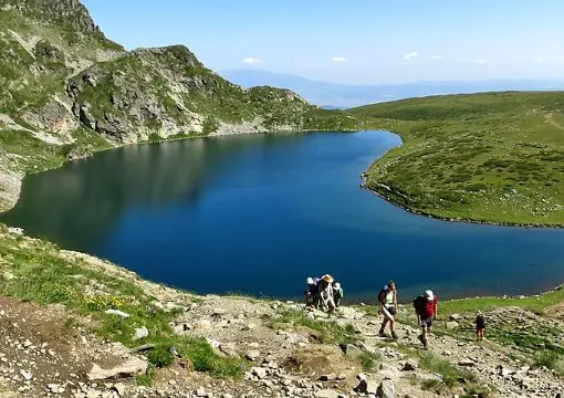 Hikers walking below a Rila lake
