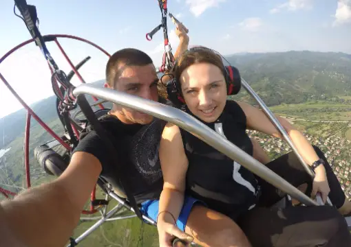 Couple taking a selfie in the motor paraglider above the hills