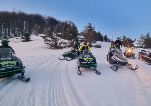 Column of snowmobiles on a groomed trail at Petrohan