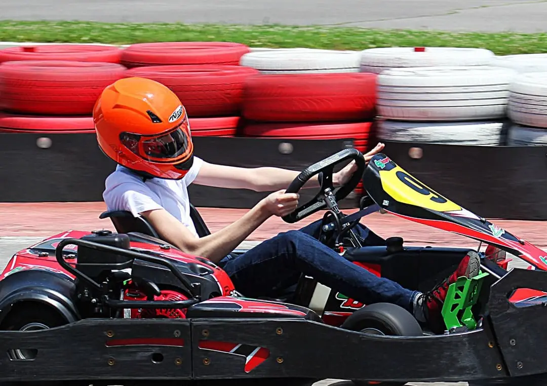Driver in an orange helmet on the outdoor track