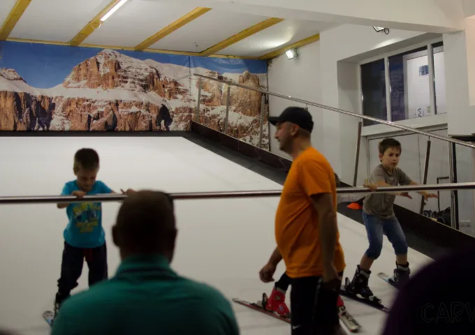Instructor helping children on the indoor slope at CARVE