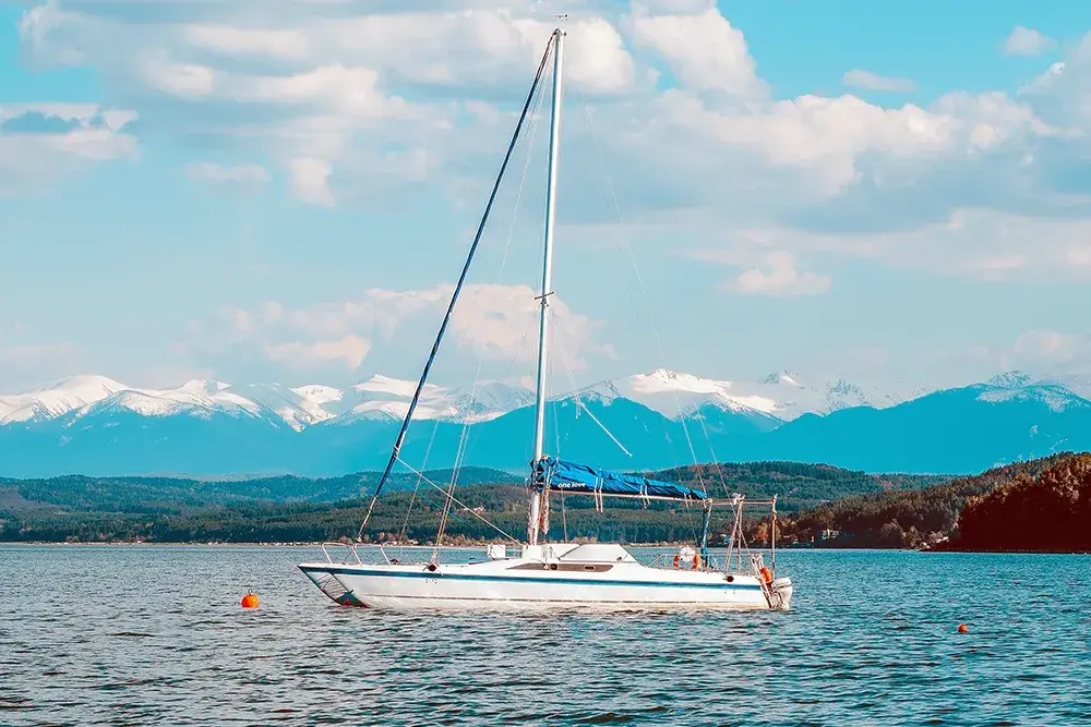 Catamaran on the reservoir with snowy mountains behind