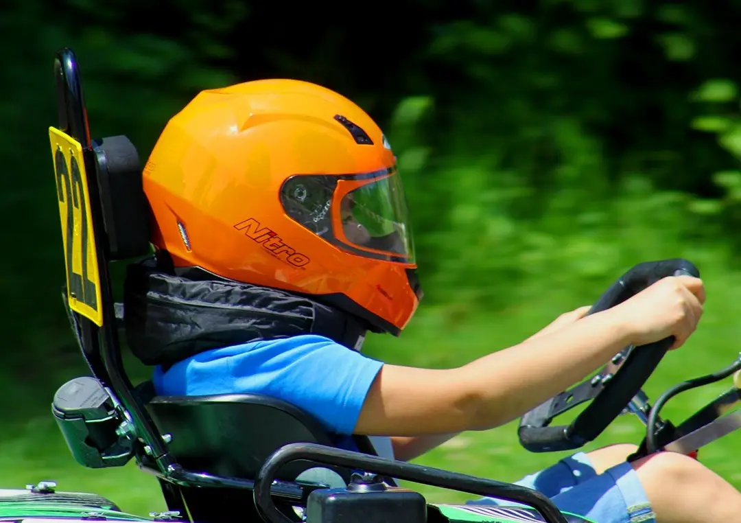 Young driver in an orange helmet in a kids’ kart