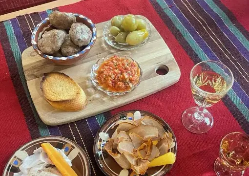 Bulgarian appetisers and rakia glasses on a woven tablecloth