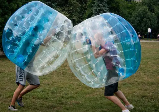Two players in bubbles pushing shoulder to shoulder on the grass