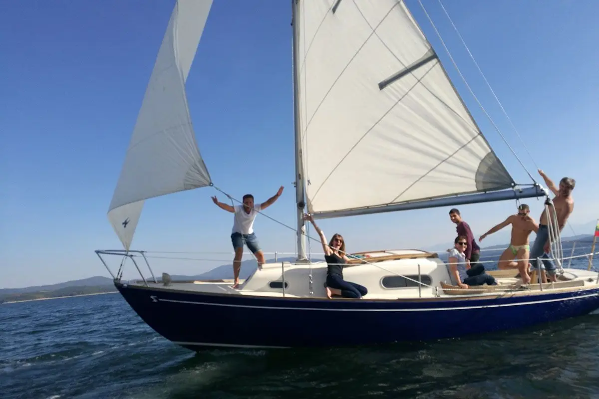 Friends cheering on a sailing yacht under full sail