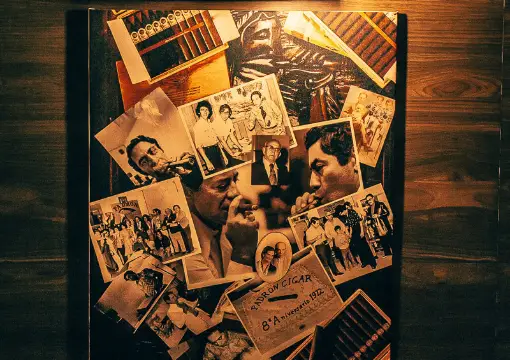 Wall of old photographs under a warm lamp at Bar Caldo