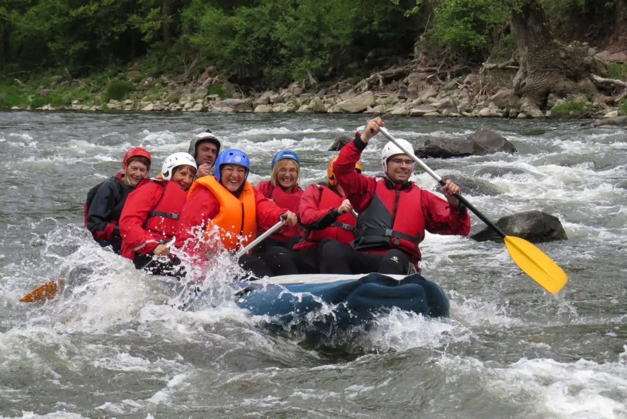 Rafters cheering with their paddles up in a blue raft