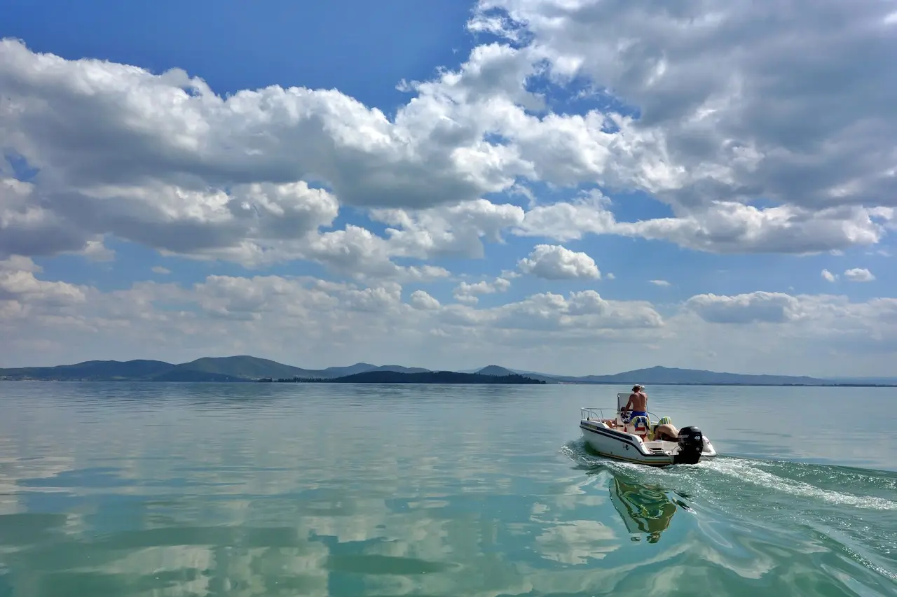 Driver steering a small outboard boat on calm water