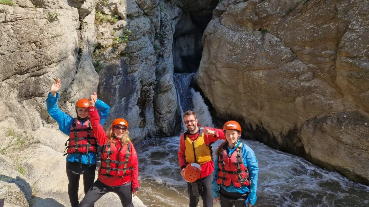 Group in helmets and life jackets in front of a waterfall at Kazanite