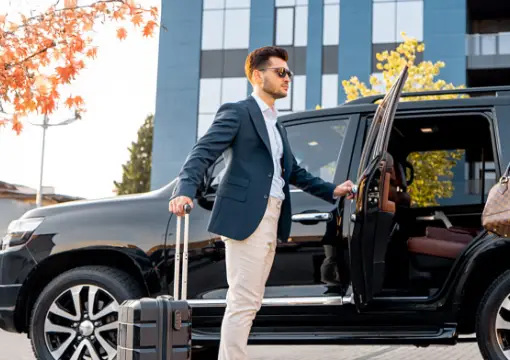 Driver opening the car door for a passenger with a suitcase
