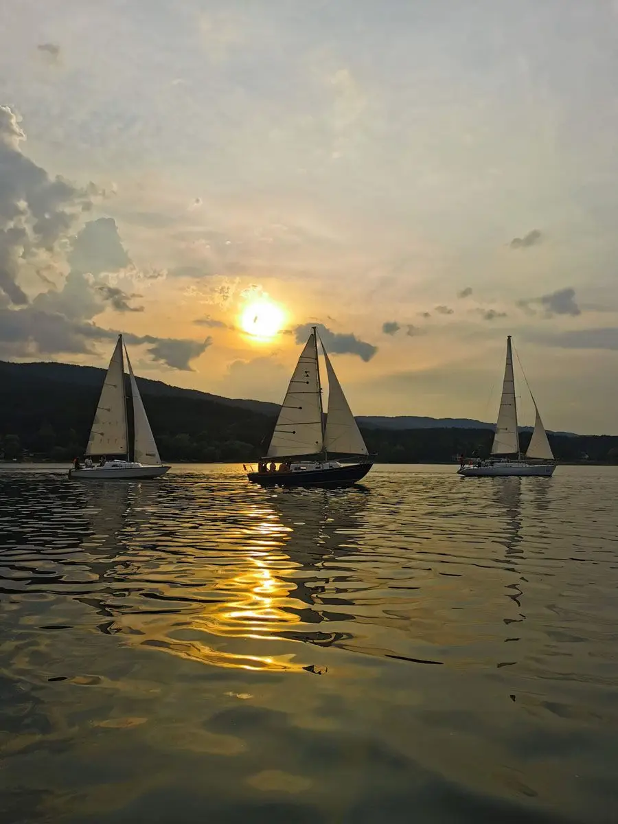 Three sailing yachts on the reservoir as the sun goes down