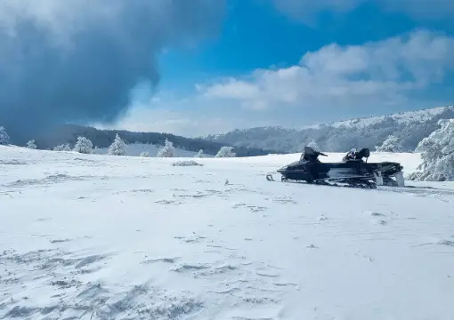 Snowmobiles on the high ridge under a dramatic winter sky