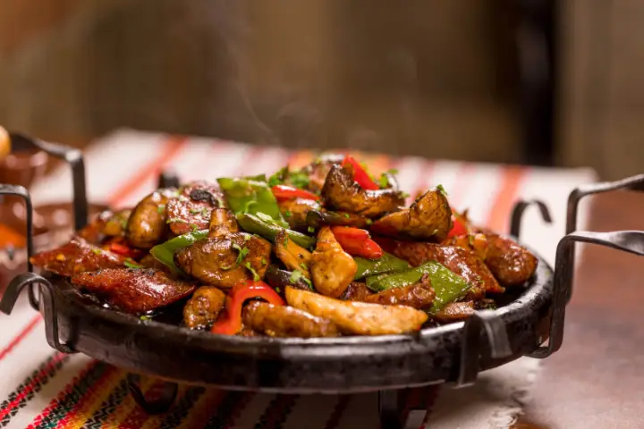 A sizzling sach skillet of meat and peppers at Izbata Tavern, Sofia