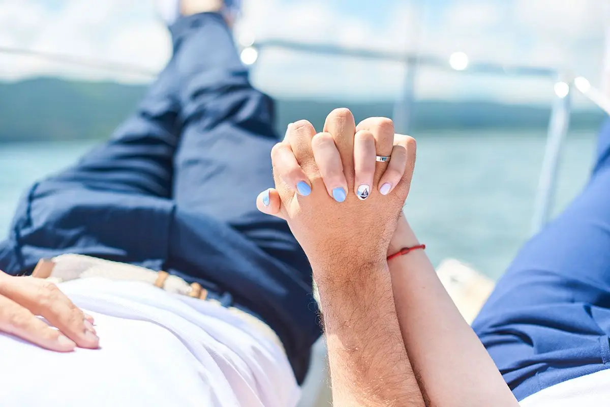 Couple holding hands on the deck of a sailing yacht