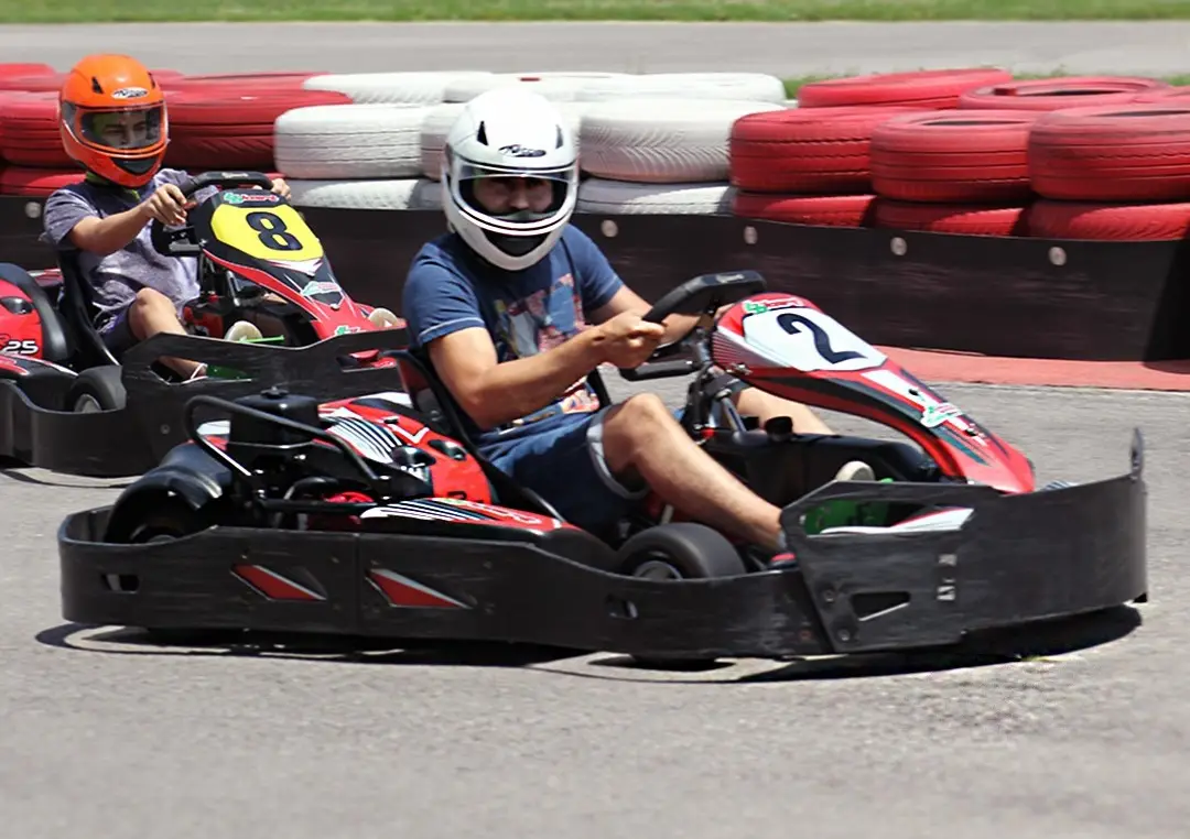 Driver in a white helmet taking a corner in an adult kart