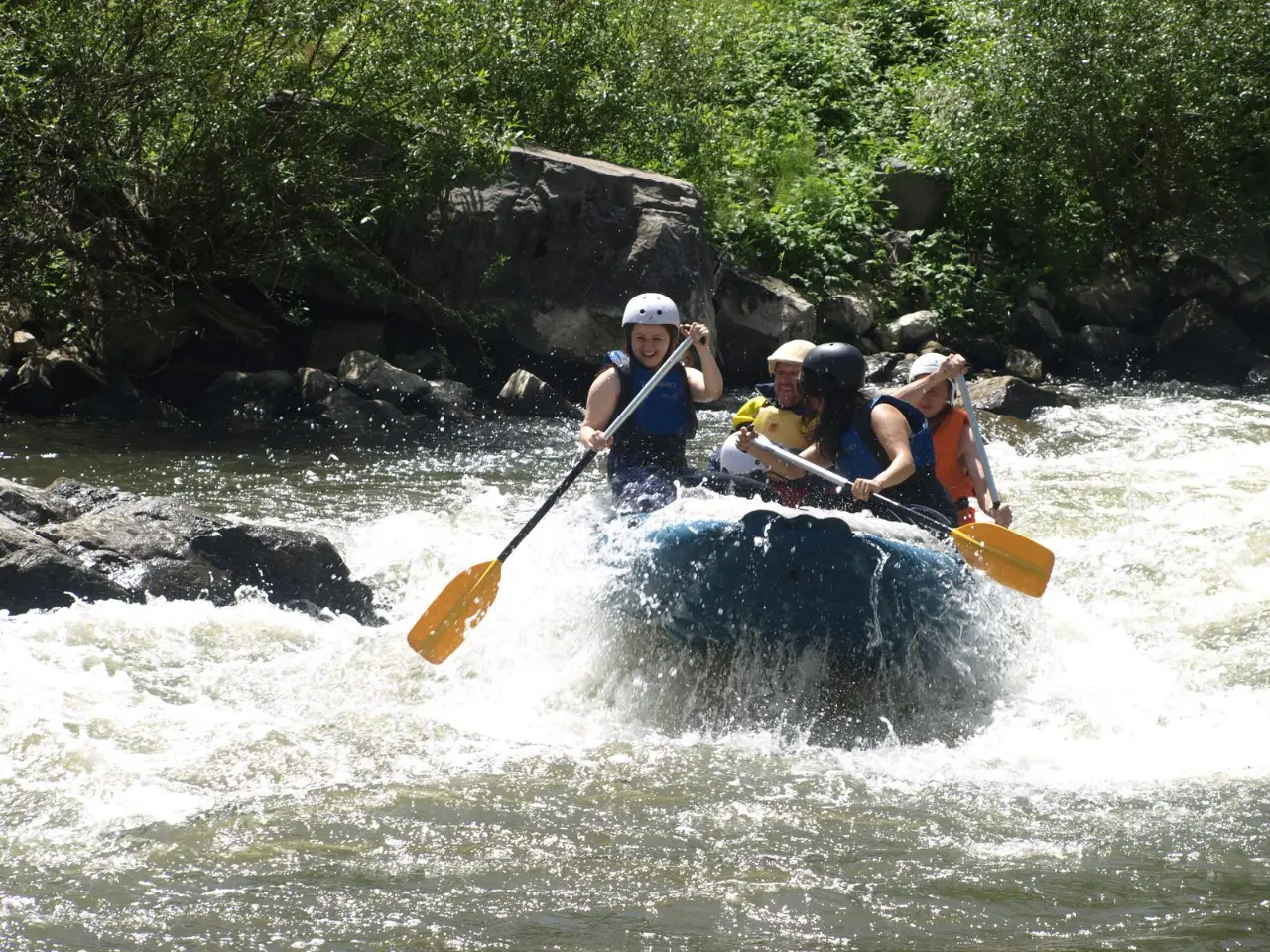 Small crew steering a raft through foaming water